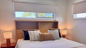 A bedroom with a bed, nightstands, a ceiling fan, and windows.