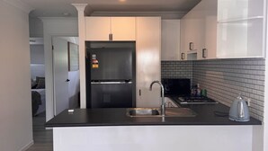 A modern kitchen with a central island, stainless steel appliances, and a tiled backsplash.