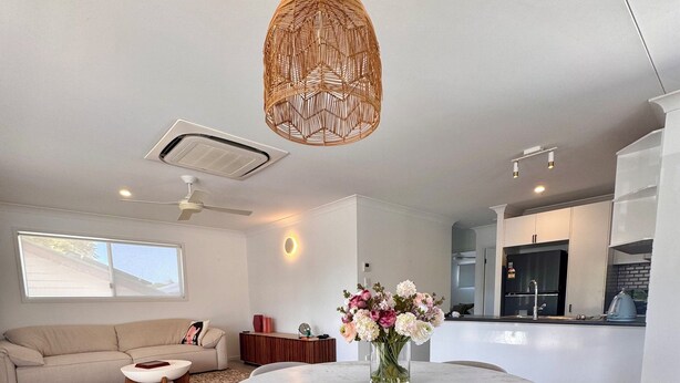 A modern living room with a round dining table, two chairs, a sofa, a coffee table, and a decorative hanging light fixture.