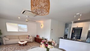 A modern kitchen with a built-in fridge, a dining area with a round table and chairs, and a living room with a sofa and a coffee table.