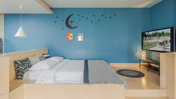 Une chambre à coucher avec un lit, une télévision, une fresque murale et un luminaire au plafond.