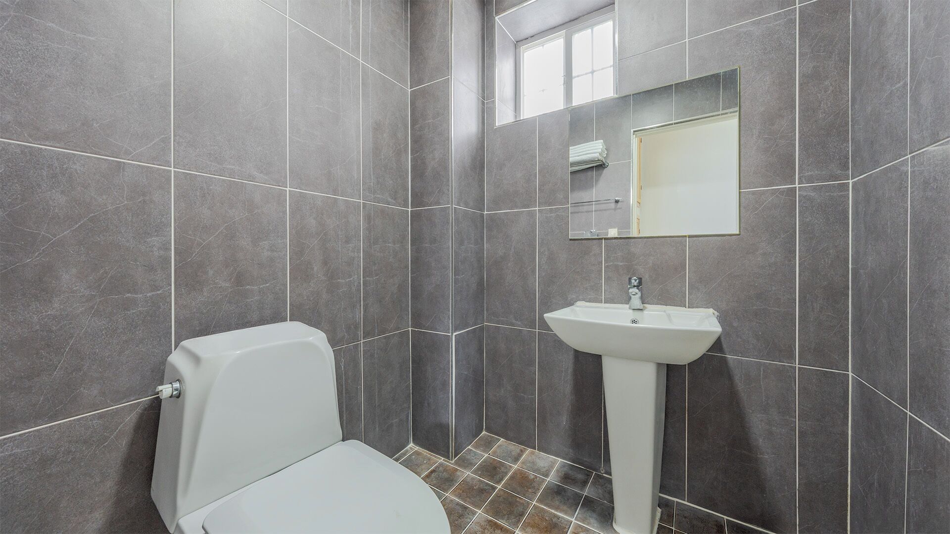 A bathroom with a toilet, sink, and mirror.