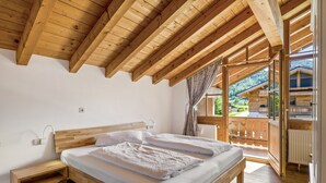 Une chambre à coucher avec un cadre en bois, comprenant un lit, des tables de chevet et une vue sur un paysage montagneux.