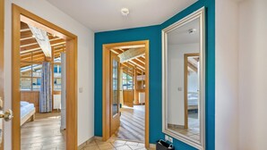 Un couloir doté d’un plancher en bois, d’un grand miroir et d’un banc.