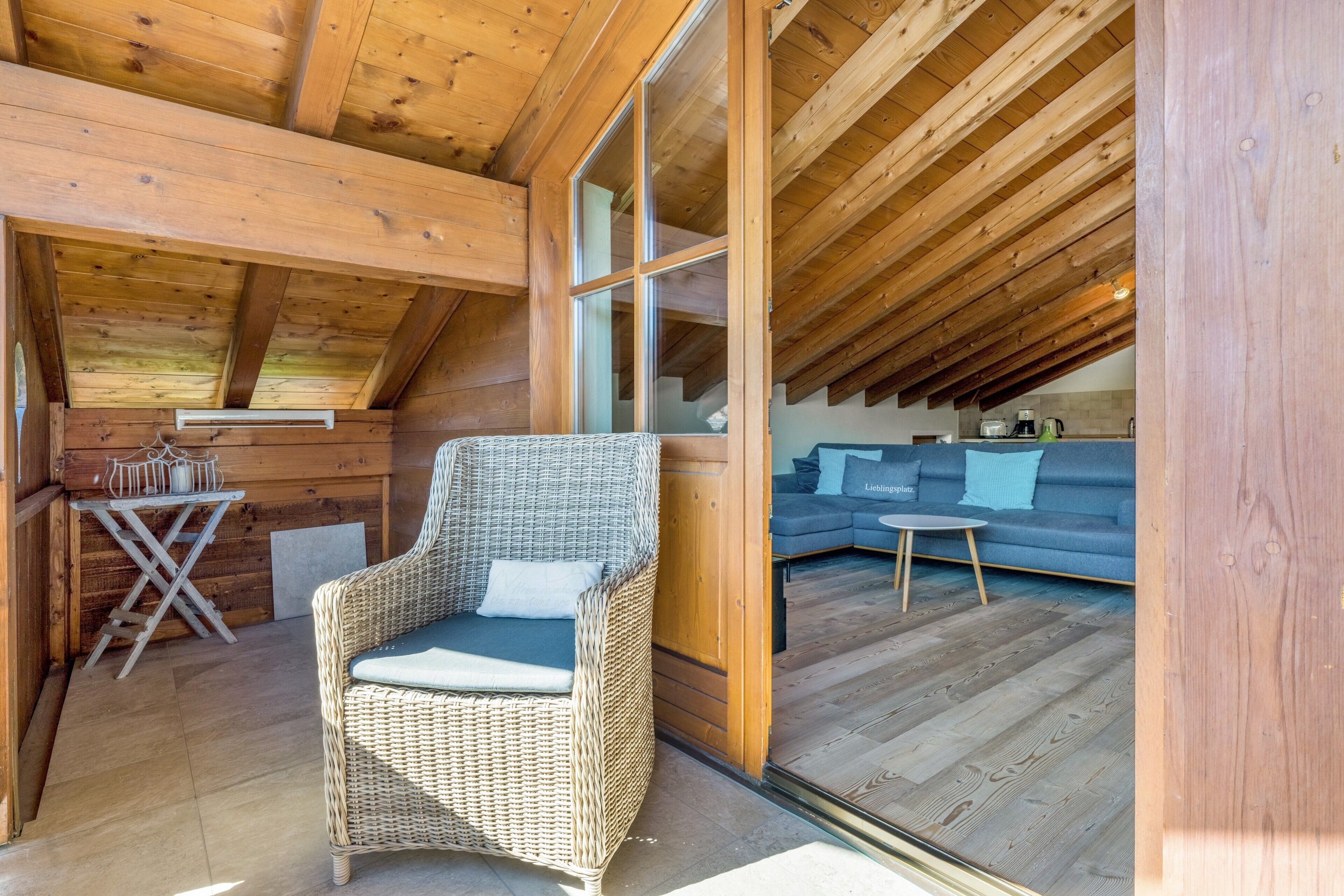 A wooden interior with a wicker chair, a small table, and a sofa.