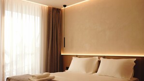 Una habitación de hotel con cama, cortinas y una lámpara fijada a la pared.