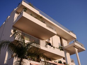 A multi-story building with balconies, some with plants.