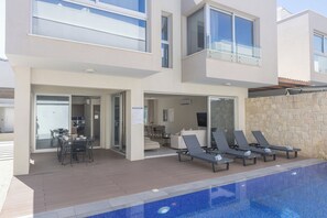 Ein modernes, zweistöckiges Gebäude mit Pool, Außenbereich und einer Steinmauer.