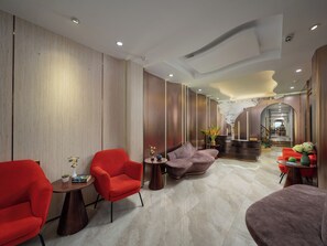Un lobby moderno con una recepción, un área de estar y una escalera que sube a otro nivel.