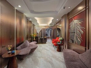 Un hall d'entrée moderne avec des sièges confortables, un comptoir de réception et une grande œuvre d'art murale.