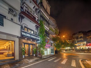 Un hotel con fachada moderna, entrada visible y vista a la calle de noche.