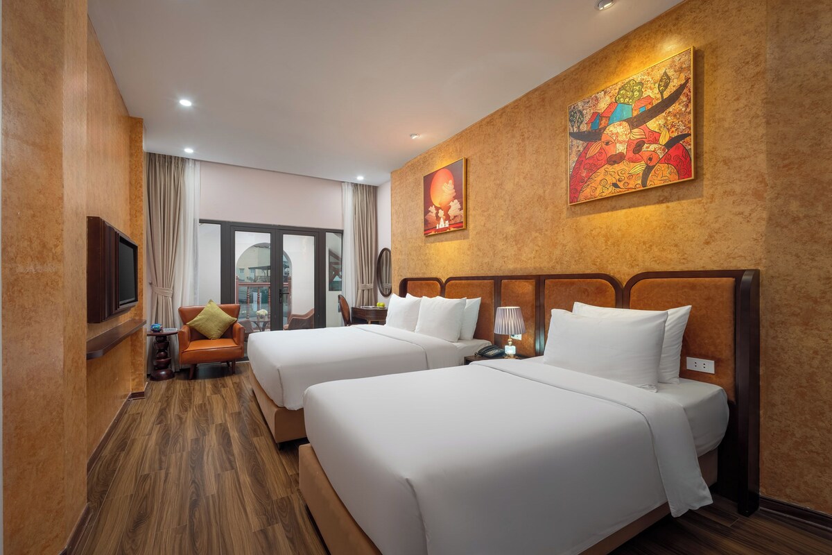 Ein Hotelzimmer mit zwei Betten, einem Fernseher, einer Couch und einem großen Fenster.