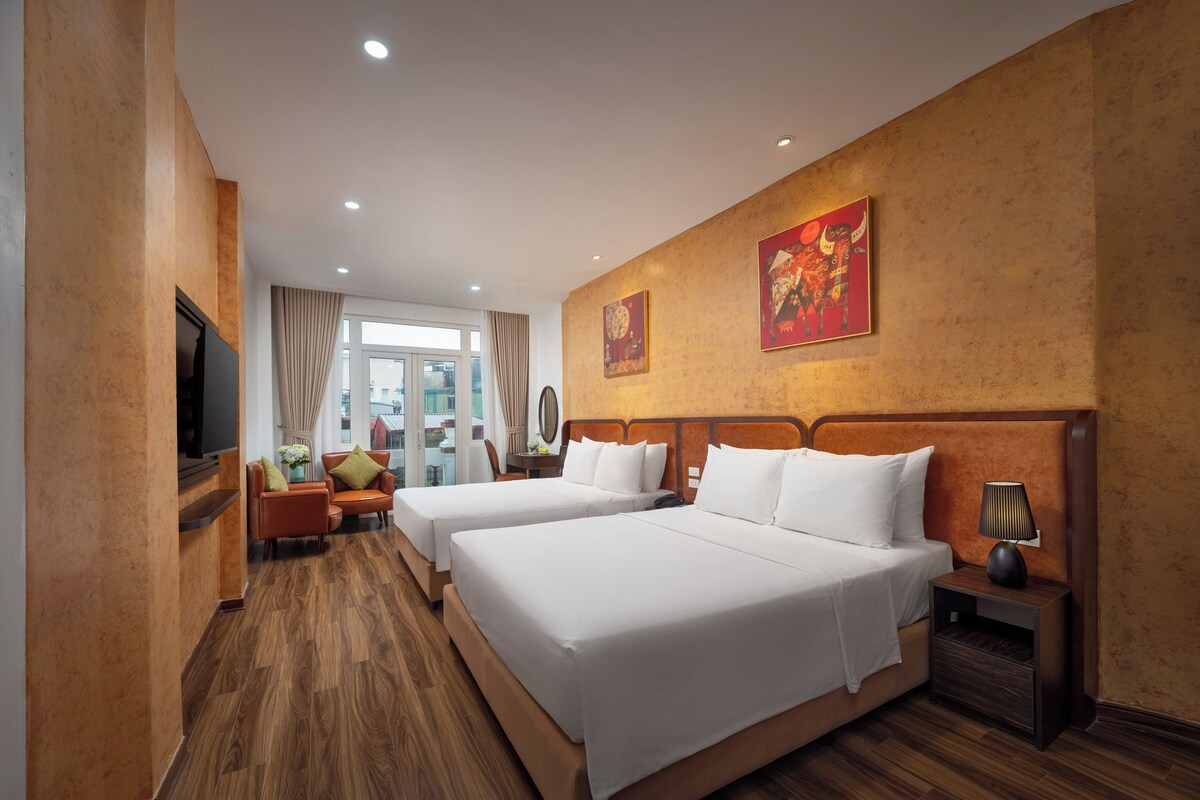 Ein Hotelzimmer mit zwei Betten, einem Fernseher, einem Schreibtisch und einem Stuhl.