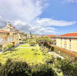 Zona residenziale con edifici, un prato verde e cielo sereno.