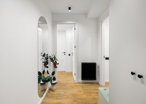 Ein Flur mit weißen Wänden, Holzboden, einem Heizkörper und einem Blumentopf.