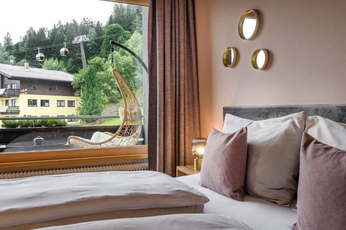 A hotel room with a bed, a view of a mountain, and a chair by the window.