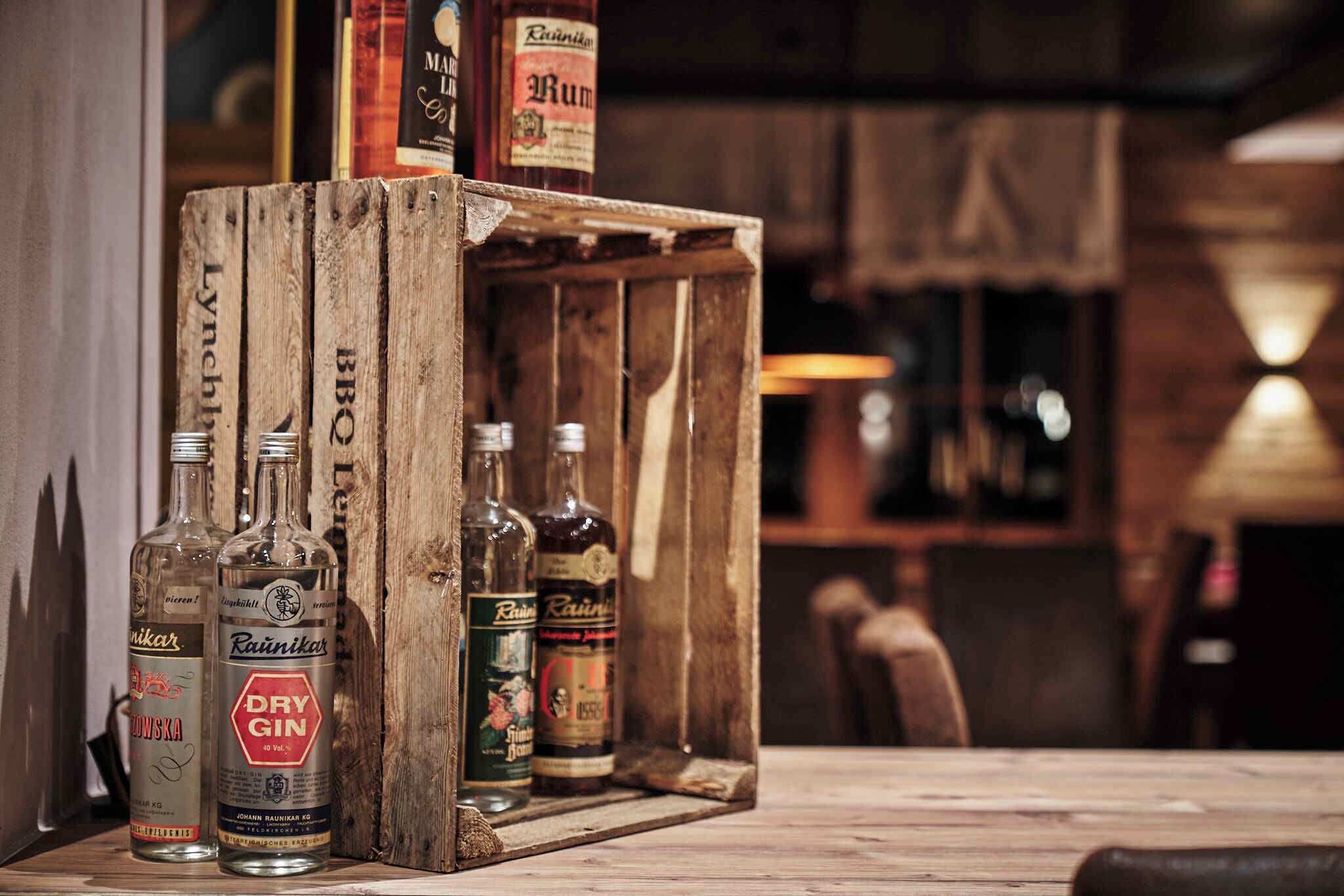 A wooden crate with bottles of liquor, including a bottle labeled 'Dry Gin.'