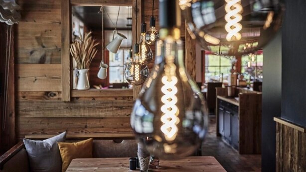 Un interior rústico con paredes de madera, una mesa de madera y lámparas colgantes.