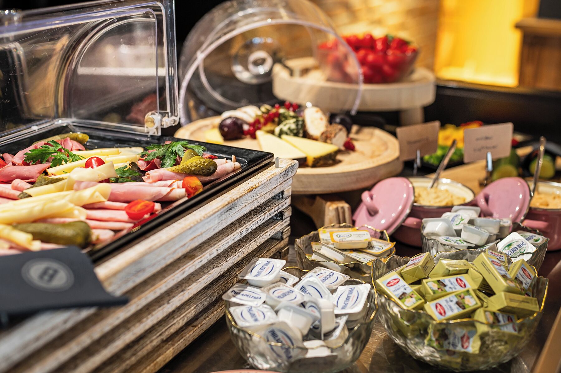 Ein reichhaltiges Buffet mit verschiedenen Speisen, darunter Fleisch, Käse und Soßen.