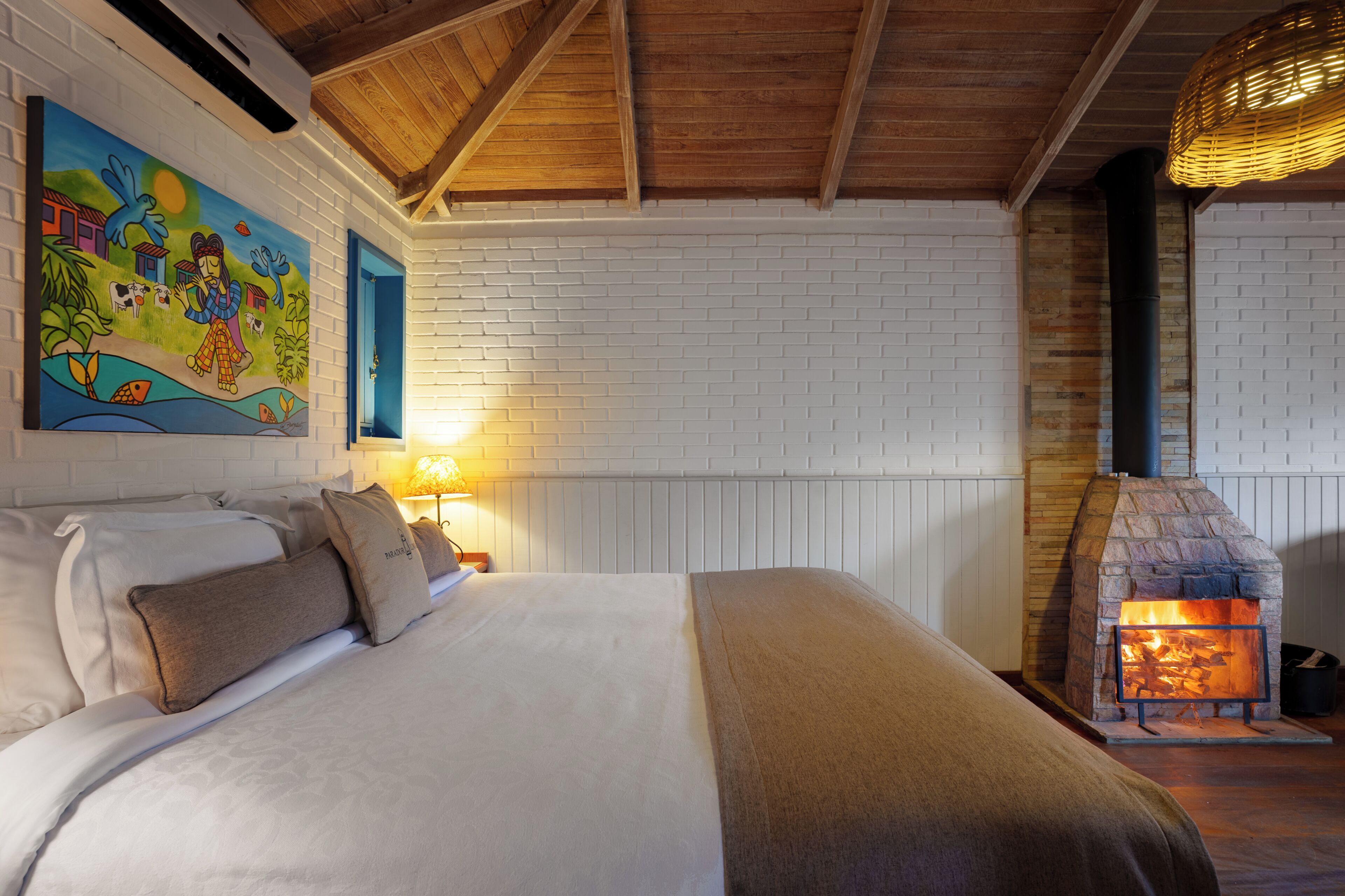 Un dormitorio con una cama grande, una chimenea de ladrillo y un mural colorido en la pared.