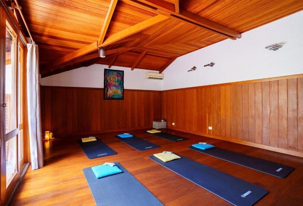 Uma sala de yoga com paredes de madeira, teto inclinado e tapetes de exercício dispostos no chão.