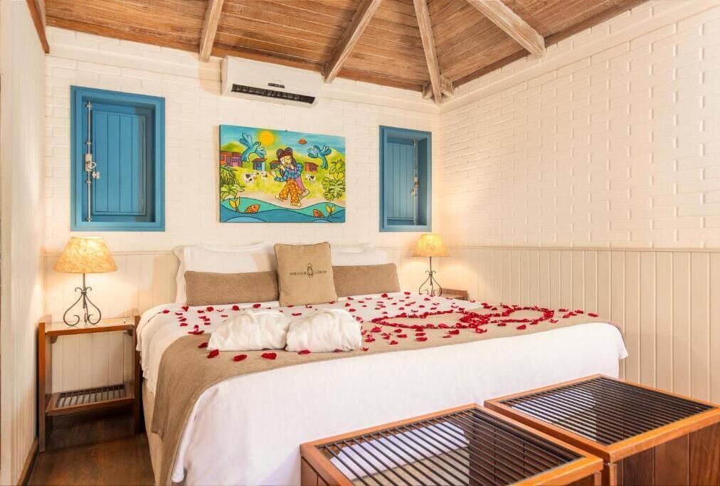 Une chambre à coucher avec un lit, deux tables de chevet, un tableau et un plafond en bois.