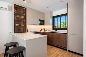A modern kitchen with a central island, built-in microwave, and a window with a view. - Luxury Golf Townhouse in Aloha with Pool & Garden (Marbella)