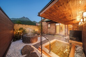 Een wellnessruimte met jacuzzi's, een houten terras en uitzicht op de bergen.