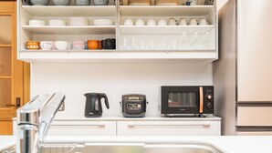 Une cuisine avec des meubles blancs, un four à micro-ondes, une machine à café et divers ustensiles de cuisine.