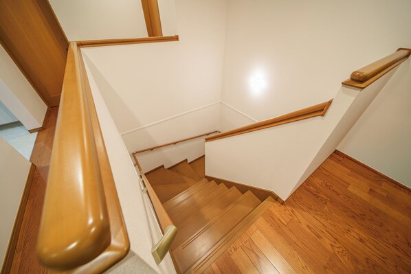 A wooden staircase with a handrail, leading to a landing with a wooden floor.