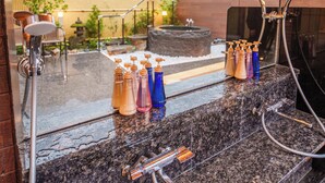 A bathroom with a granite countertop, multiple showerheads, and a variety of toiletries. - KINNOKA YUNOYADO (Yufu)