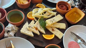 Une table garnie de divers aliments, notamment du fromage, de la charcuterie et du pain.