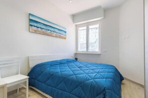 Een slaapkamer met een bed, een raam en een schilderij aan de muur.