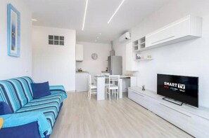 Een moderne woonkamer met een bank, een eettafel en een televisie.