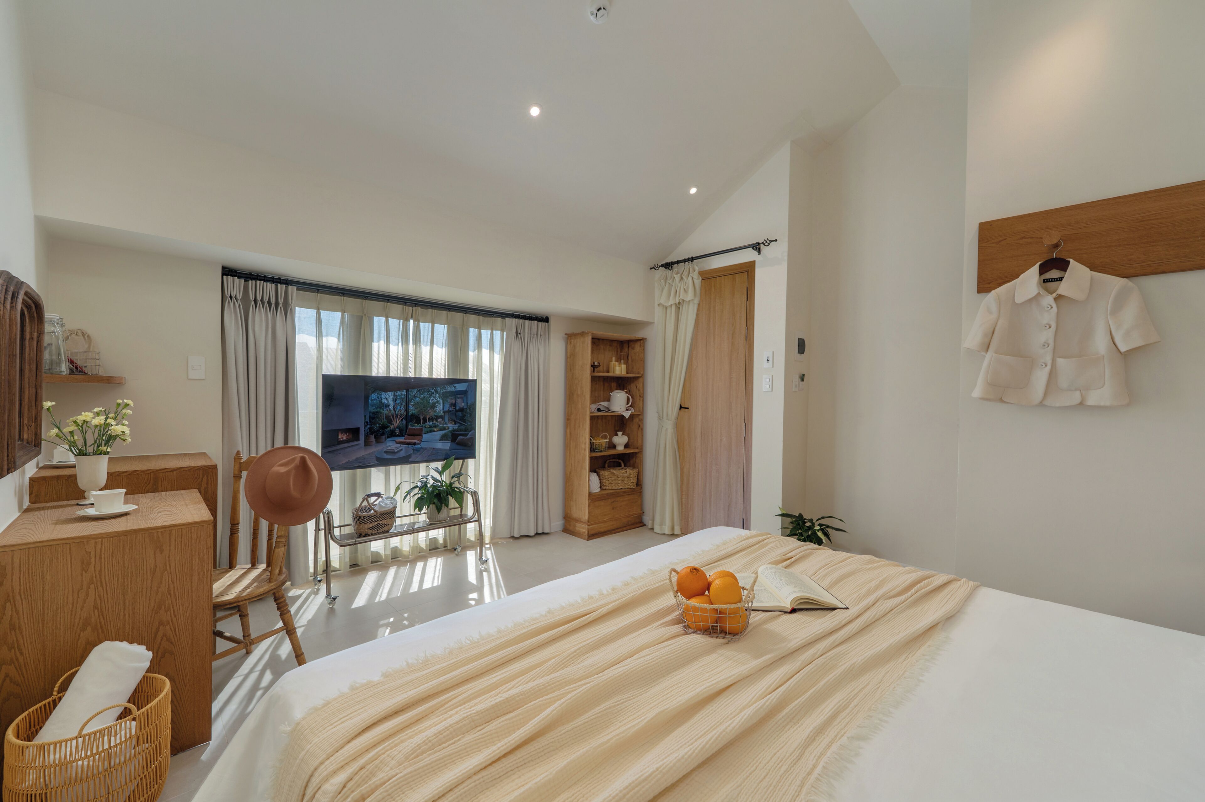 A modern hotel room with a large bed, a TV, a desk, and a wardrobe.