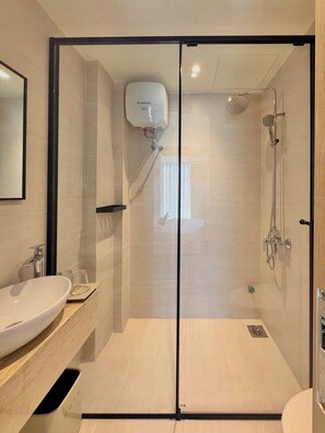 A modern bathroom with a glass-enclosed shower, a white sink, and a mirror. - Aura Zen Hotel Hoian (Hoi An)