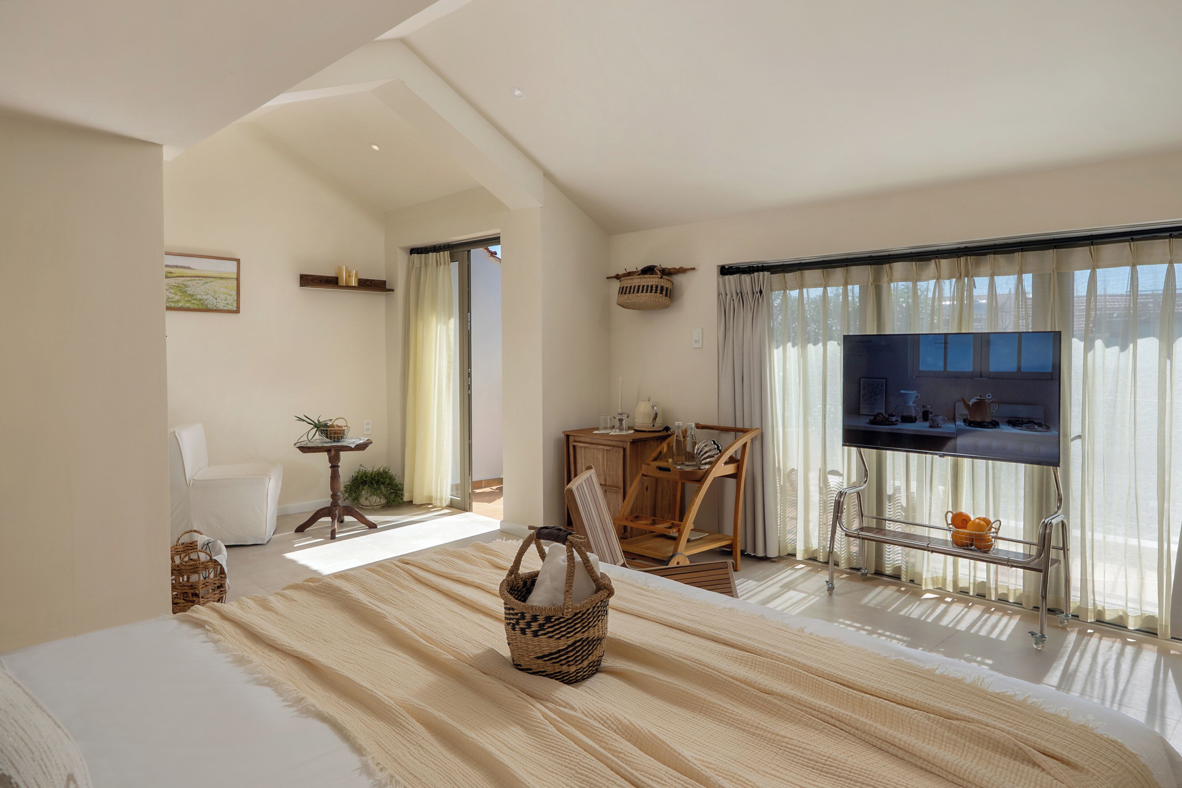 Una habitación amplia con una cama grande, televisión, zona de comedor y vistas por la ventana.