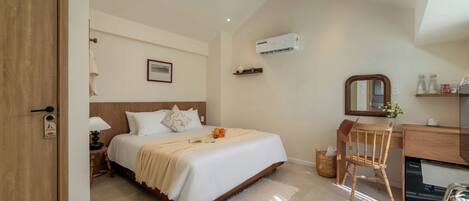 A bedroom with a bed, bedside table, lamp, chair, desk, mirror, and air conditioning unit.