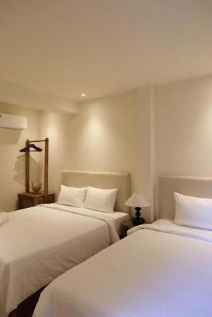 Habitación de hotel con dos camas, una mesita de noche con lámpara y un espejo.