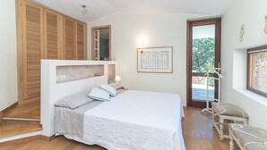 Un dormitorio con cama, armario de madera, banca y puerta que da a un espacio exterior.