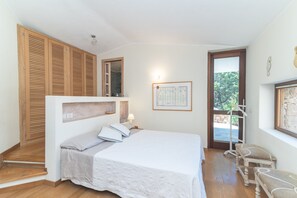 Un dormitorio con cama, armario de madera, banca y puerta que da a un espacio exterior.