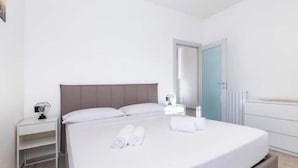 Une chambre d’hôtel avec un lit, une table de chevet, un miroir et une porte.