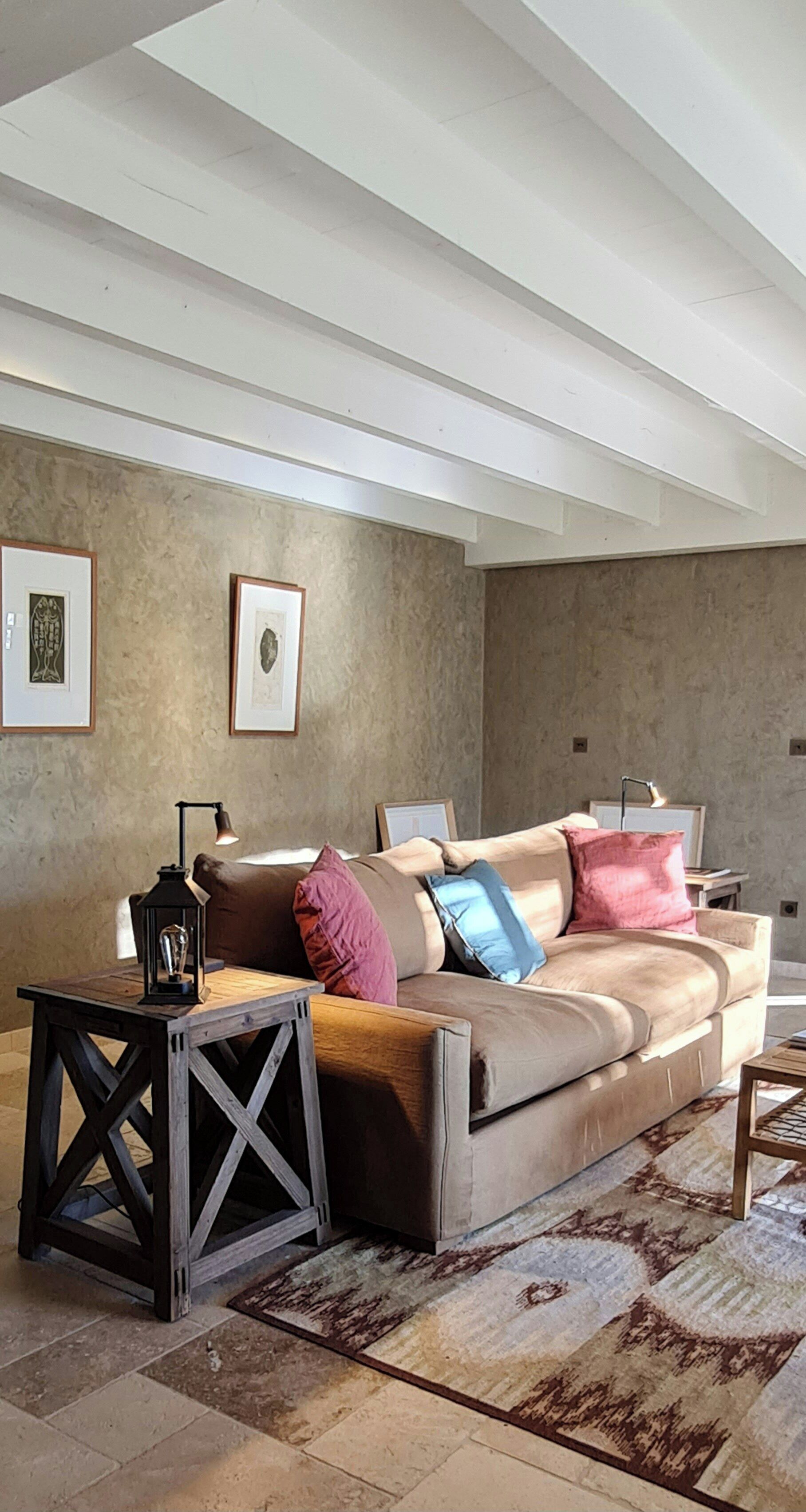A modern living room with a sofa, a side table, a lamp, and framed artwork on the wall.