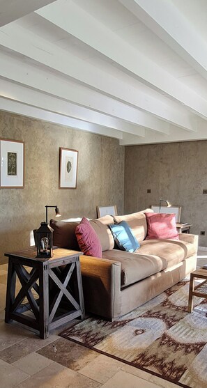 A modern living room with a sofa, a side table, a lamp, and framed artwork on the wall.