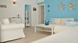 A modern living room with a white sofa, a white coffee table, and a blue accent wall. - Palau Noal (Alghero)
