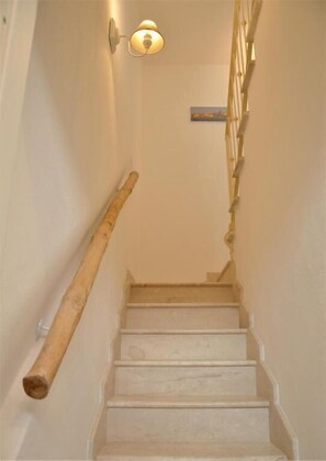 A staircase with wooden handrails and a wall-mounted light fixture. - Palau Noal (Alghero)