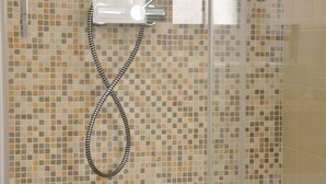 A shower enclosure with a tiled mosaic wall, a showerhead, and a control panel. - Palau Noal (Alghero)