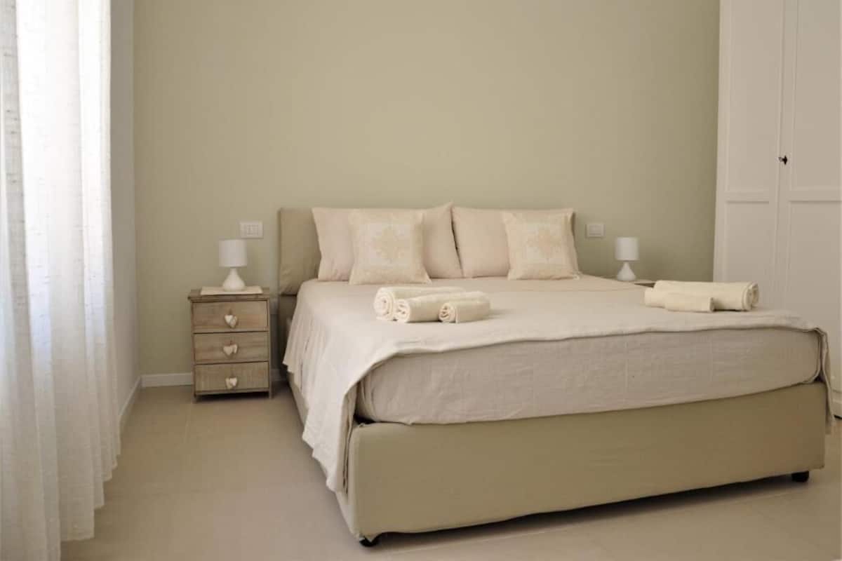 Quarto com uma cama, duas mesas de cabeceira e uma porta.