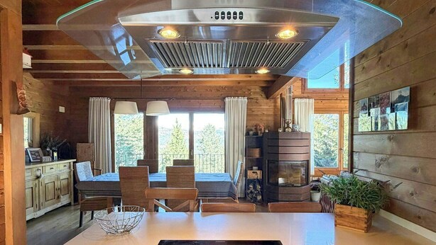Una cocina con una isla central, estufa, horno y una campana extractora grande.