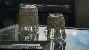 Una mesa de vidrio con dos jarrones decorativos y un control remoto.